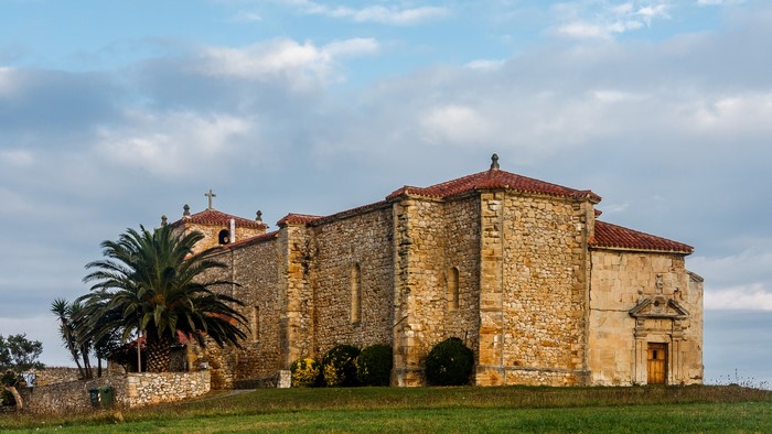 Stone church with palm tree in Cantabria, Spain