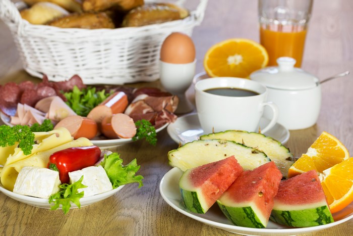 Breakfast spread with fruits, cheese, meats, and coffee