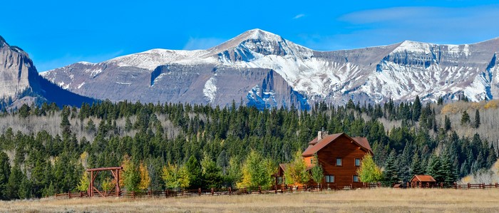 Log cabin and ranch gate with snow-capped mountains in Crested Butte, Colorado