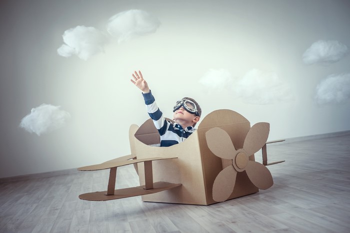 Boy in cardboard airplane with goggles