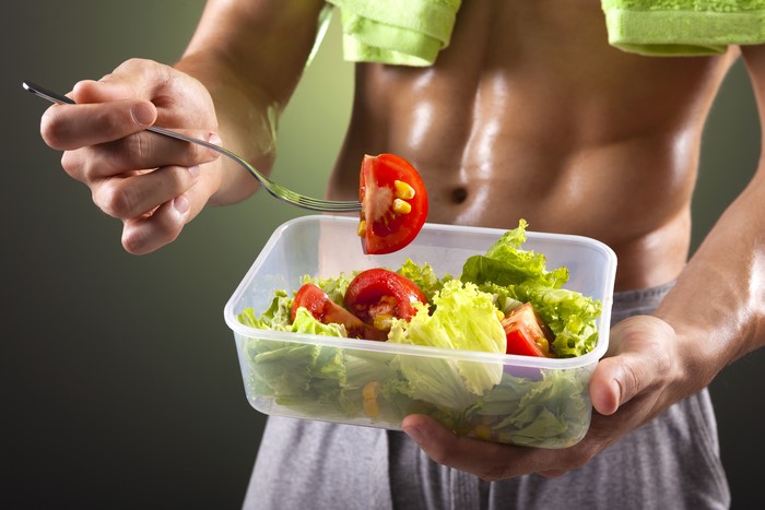 Man holding a salad with a fork