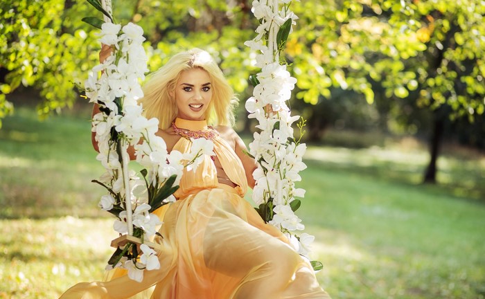 Blonde woman in a yellow dress on a swing