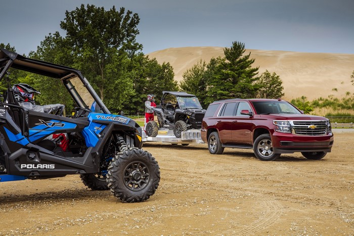Chevrolet Tahoe towing ATVs on sandy terrain