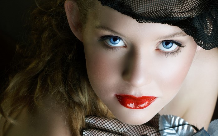 Woman with blue eyes and red lips wearing a black veil