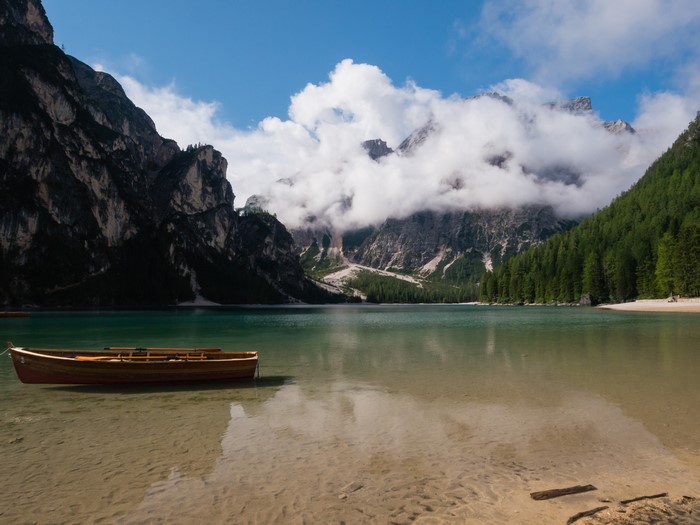Wooden boat on Lake Braies with mountains and clouds