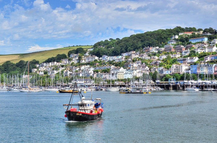 Boats in a harbor with houses on a hill in Dartmouth, England