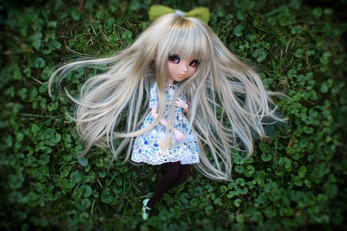 Blonde doll with long hair lying on grass