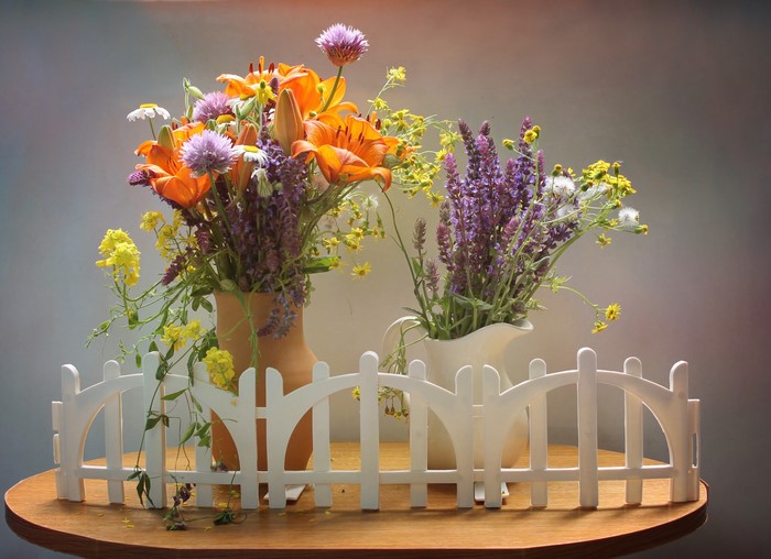 Bouquets of lilies and wildflowers with a white fence