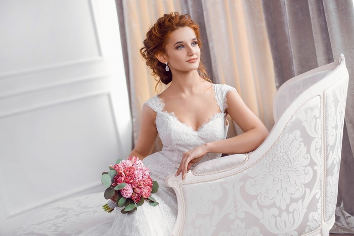 Bride with red hair holding a bouquet sitting on a couch