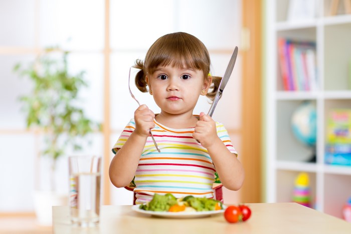 Little girl with fork and knife