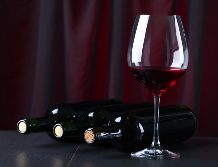 Wine bottles and glass with red curtain