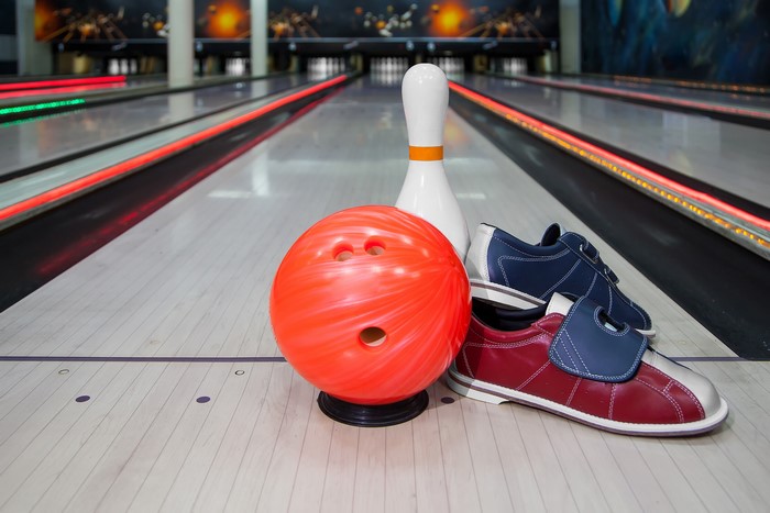 Bowling ball, pin, and shoes on lane