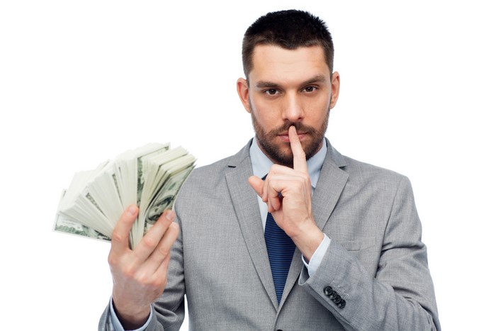 Man in Suit Holding Money and Signaling Silence