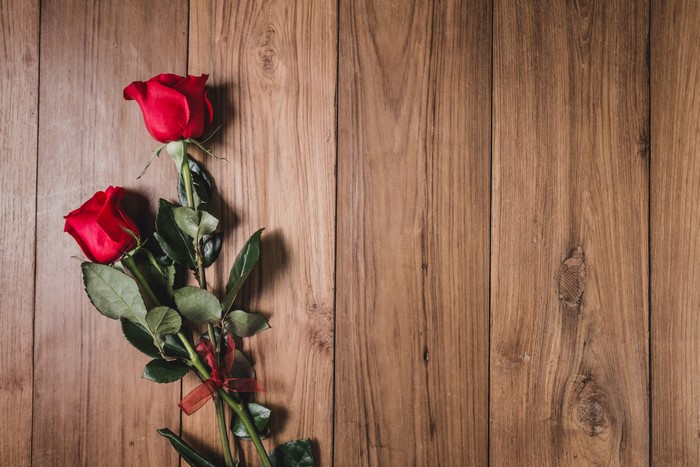 Two red roses on wood planks