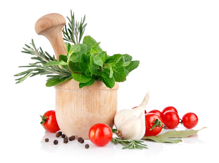 Mortar and pestle with herbs, tomatoes, garlic, and peppercorns