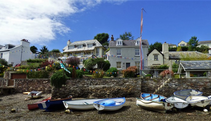 Boats on a pebble beach with houses in the background
