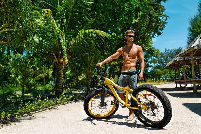 Man with bicycle on a tropical beach