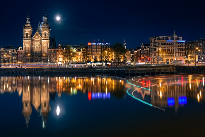 Amsterdam skyline at night with moon and river reflection
