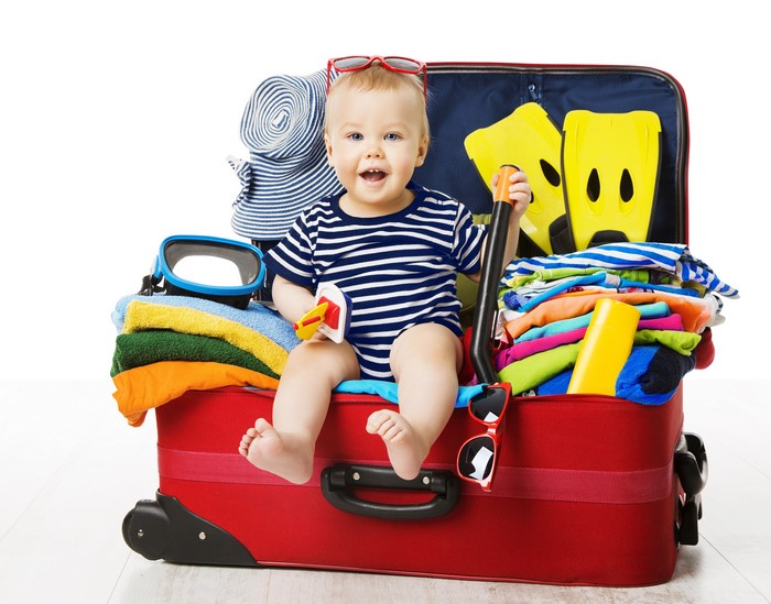 Baby sitting in a red suitcase packed for vacation
