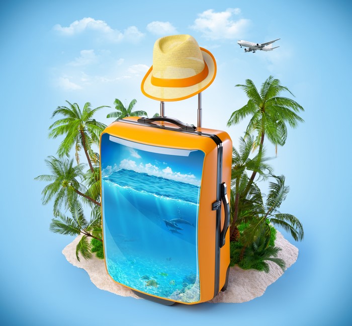 Suitcase with tropical island scene and airplane