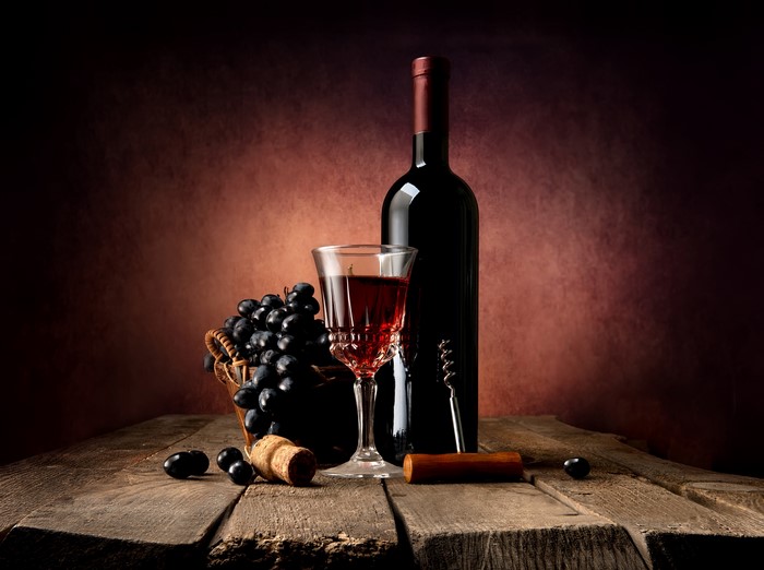 Still-life of wine bottle, glass, and grapes on wood planks