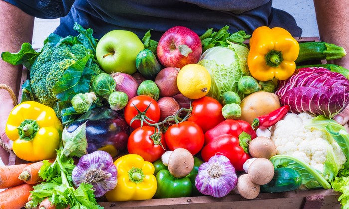 A variety of fresh vegetables and fruits in a wooden crate
