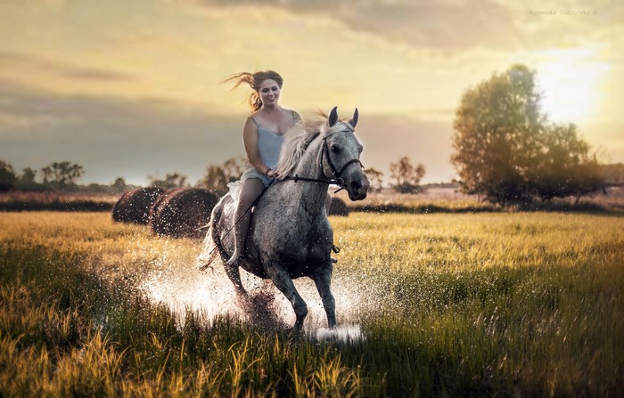 Woman riding a horse through water splash