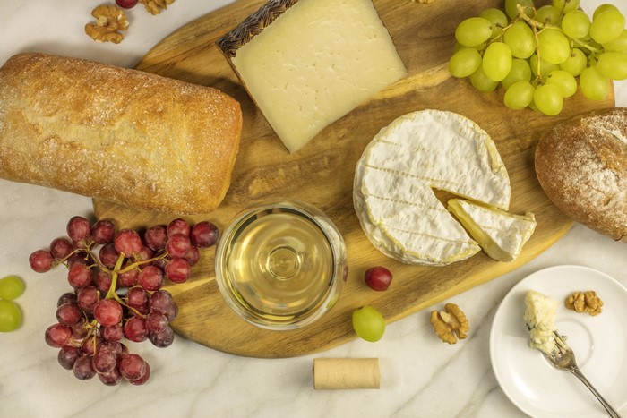 Cheese, Bread, Grapes, and Wine on a Cutting Board