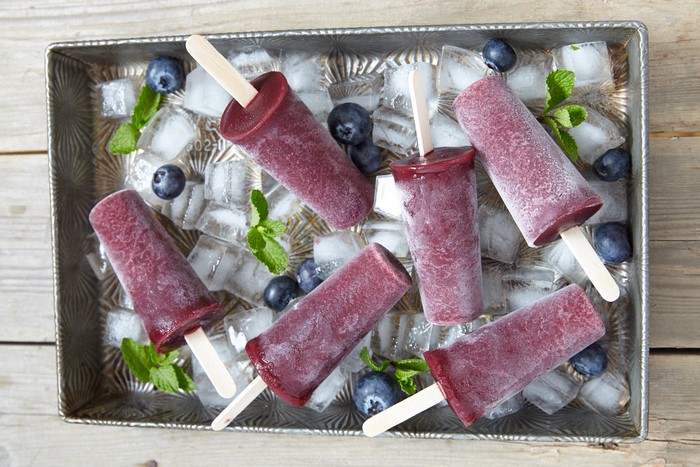 Blueberry popsicles on ice with blueberries and mint