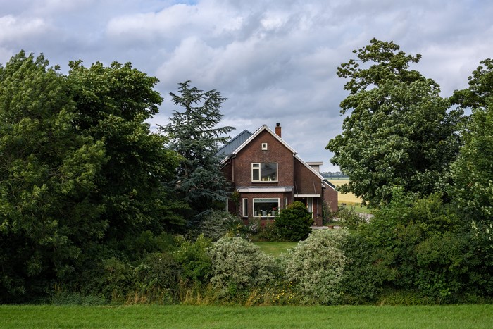 Brick house surrounded by trees in Kolhorn, Netherlands