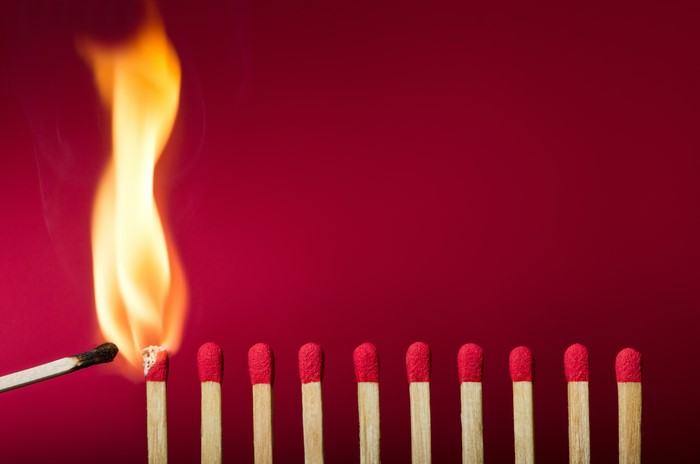 Burning match igniting others on red background