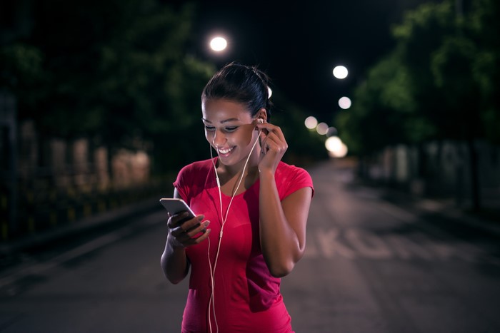 Brunette girl with headphones and smartphone at night