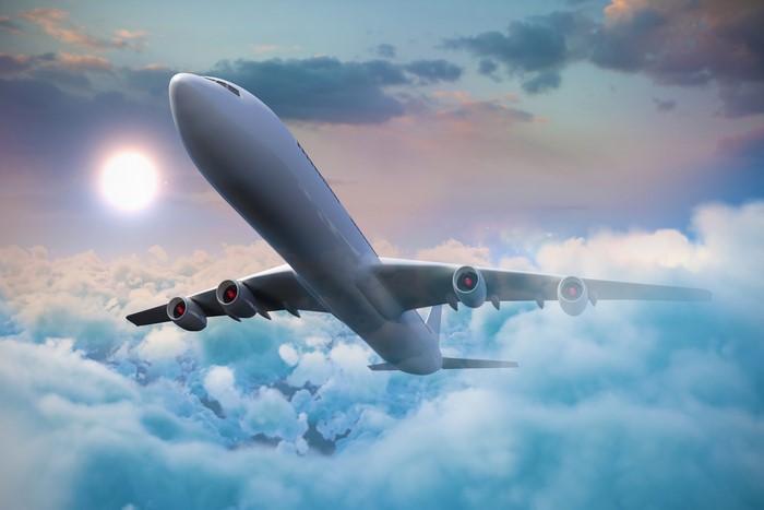 Airplane flying through clouds at sunset