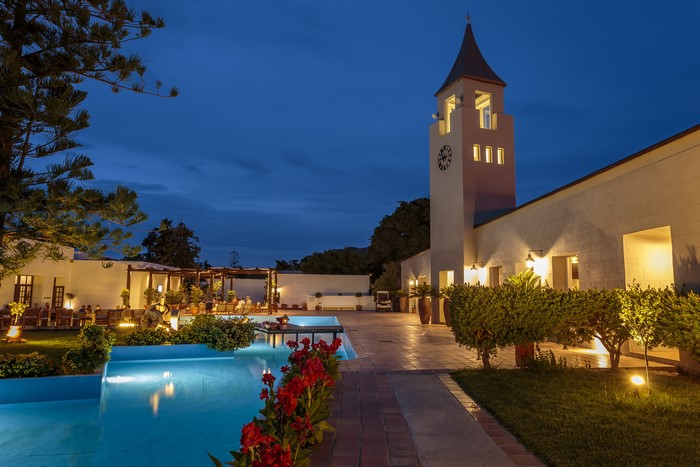 Villa with pool and clock tower at dusk