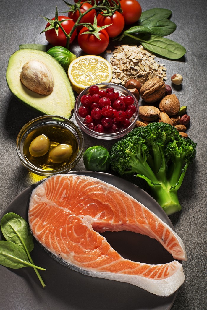 Salmon steak with avocado, tomatoes, berries, nuts, and broccoli