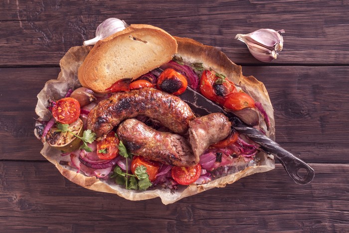 Sausages with grilled vegetables and bread on a wooden table
