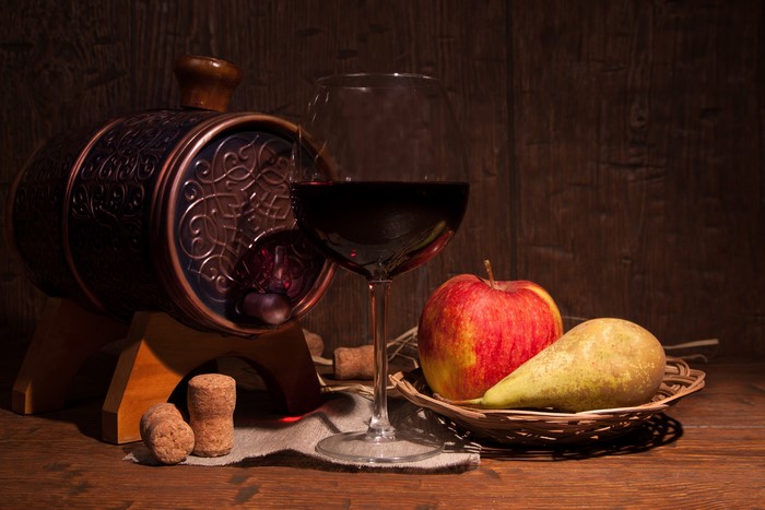 Still life with wine barrel, glass of red wine, apple, and pear