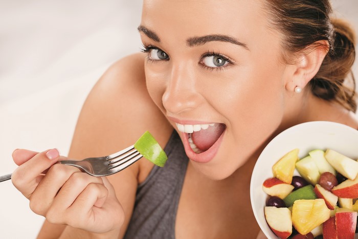 Woman eating fruit salad with a fork