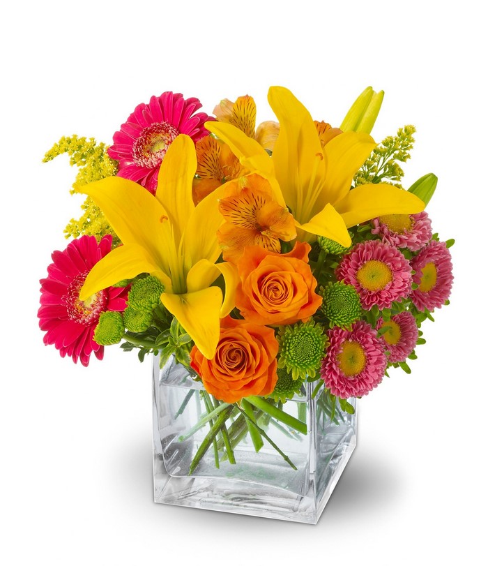 Yellow lilies, orange roses, and pink gerberas in a glass vase
