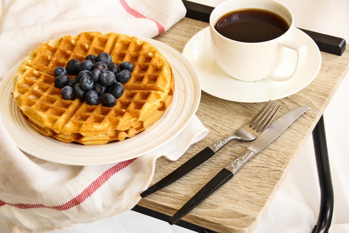 Waffles with blueberries and coffee on a tray