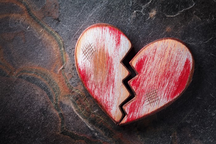 Broken wooden heart on a stone surface