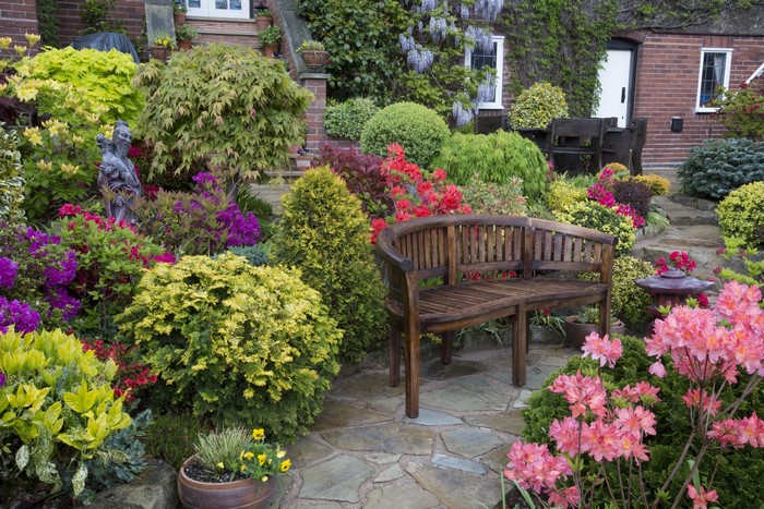 Garden with a wooden bench and colorful flowers in England