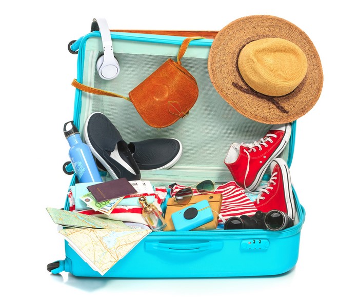 Open suitcase packed for travel with clothing and accessories