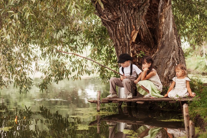 Three children fishing by a large tree