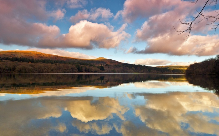 Lake reflecting clouds and hills at sunset