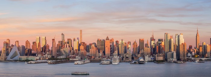 New York City skyline with skyscrapers and ships at sunset