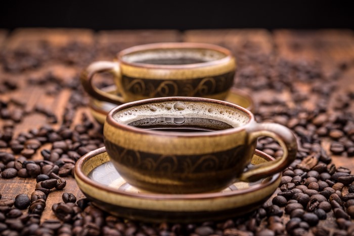 Two cups of coffee with coffee beans