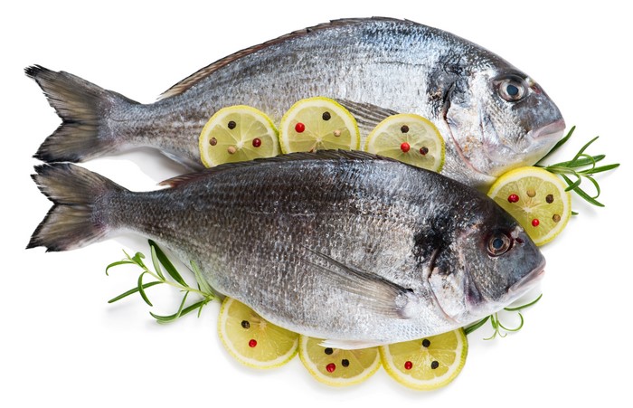 Two raw fish with lemon slices and rosemary