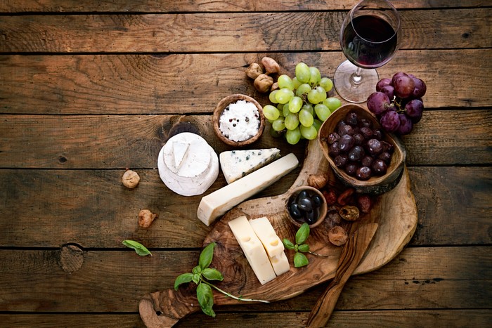 Cheese, Grapes, Olives, and Wine on Wood