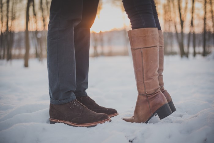Couple wearing boots in the snow at sunset